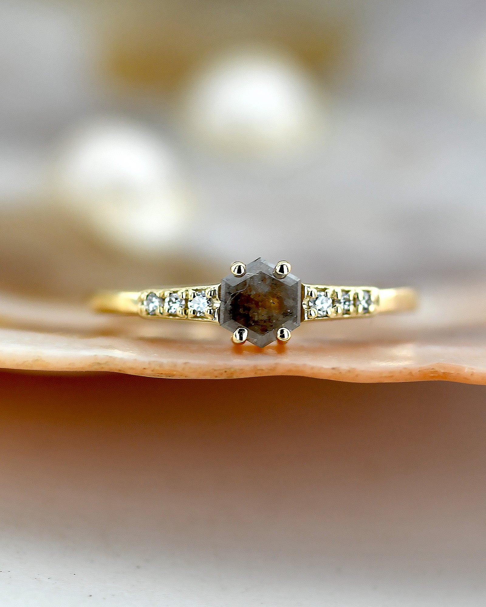 Gold ring with a central diamond and smaller diamonds on a shell background