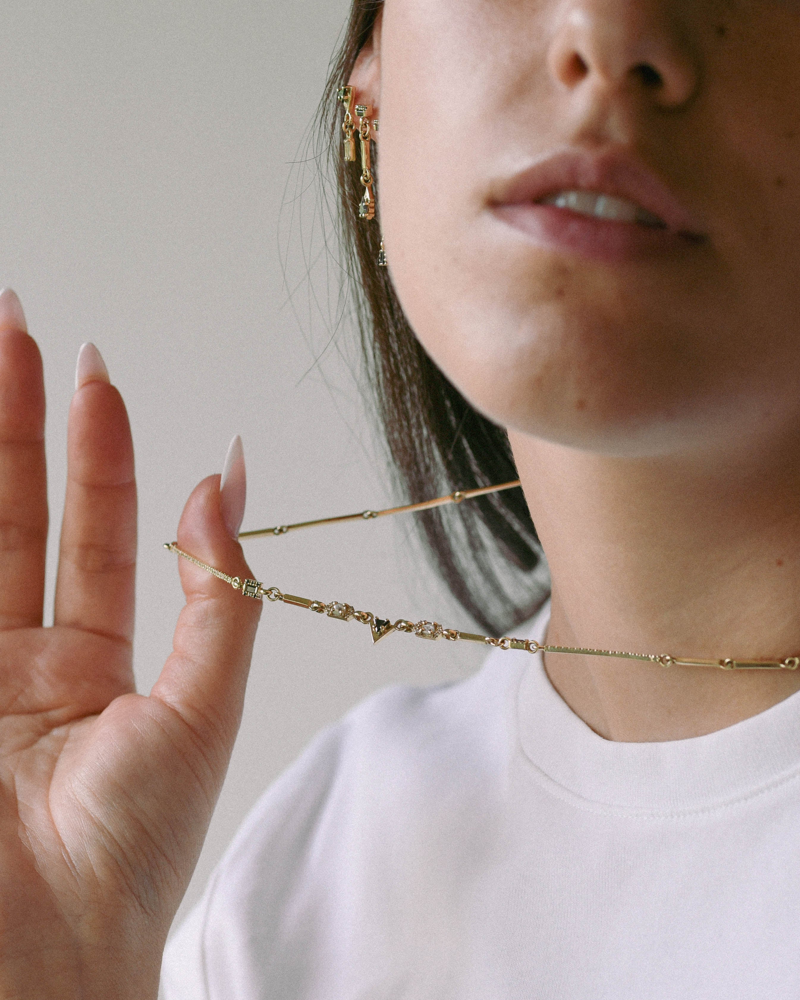 Close-up of a person wearing gold necklaces with a neutral background