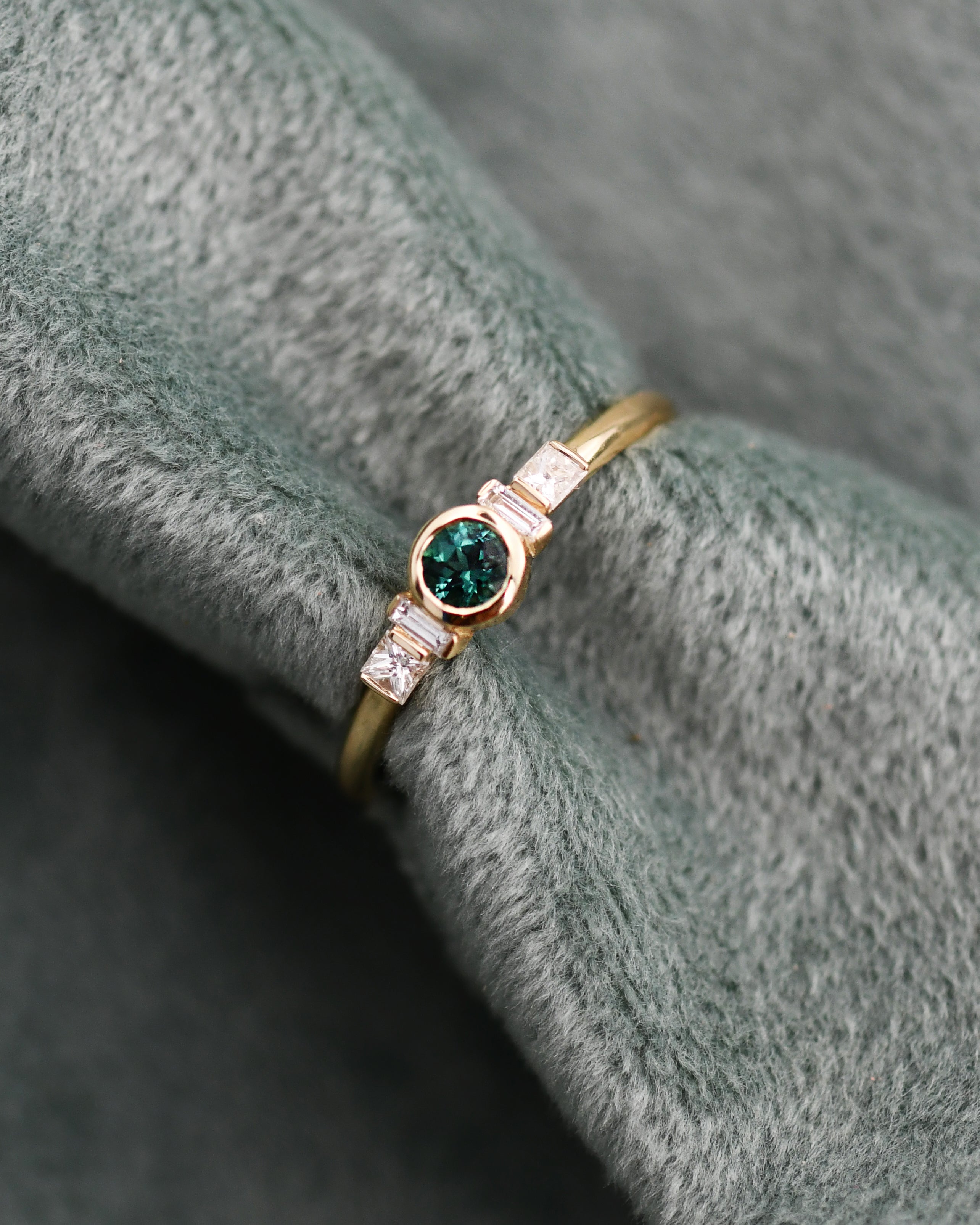 A gold ring featuring a round green tourmaline gemstone and baguette-cut clear white diamonds