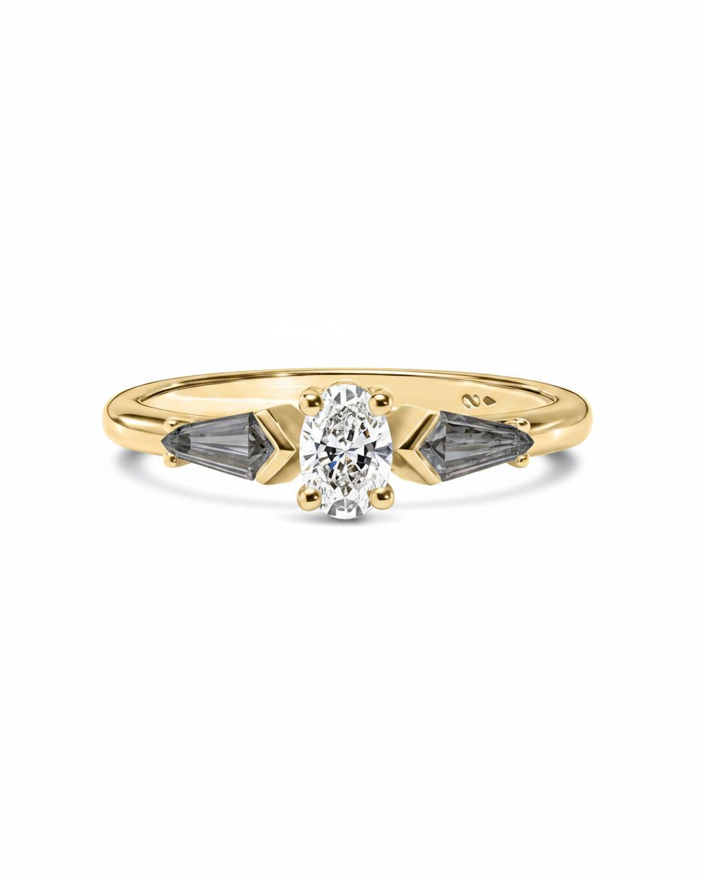 A yellow gold ring featuring a central round-cut clear gemstone flanked by two dark gray kite-cut side diamonds