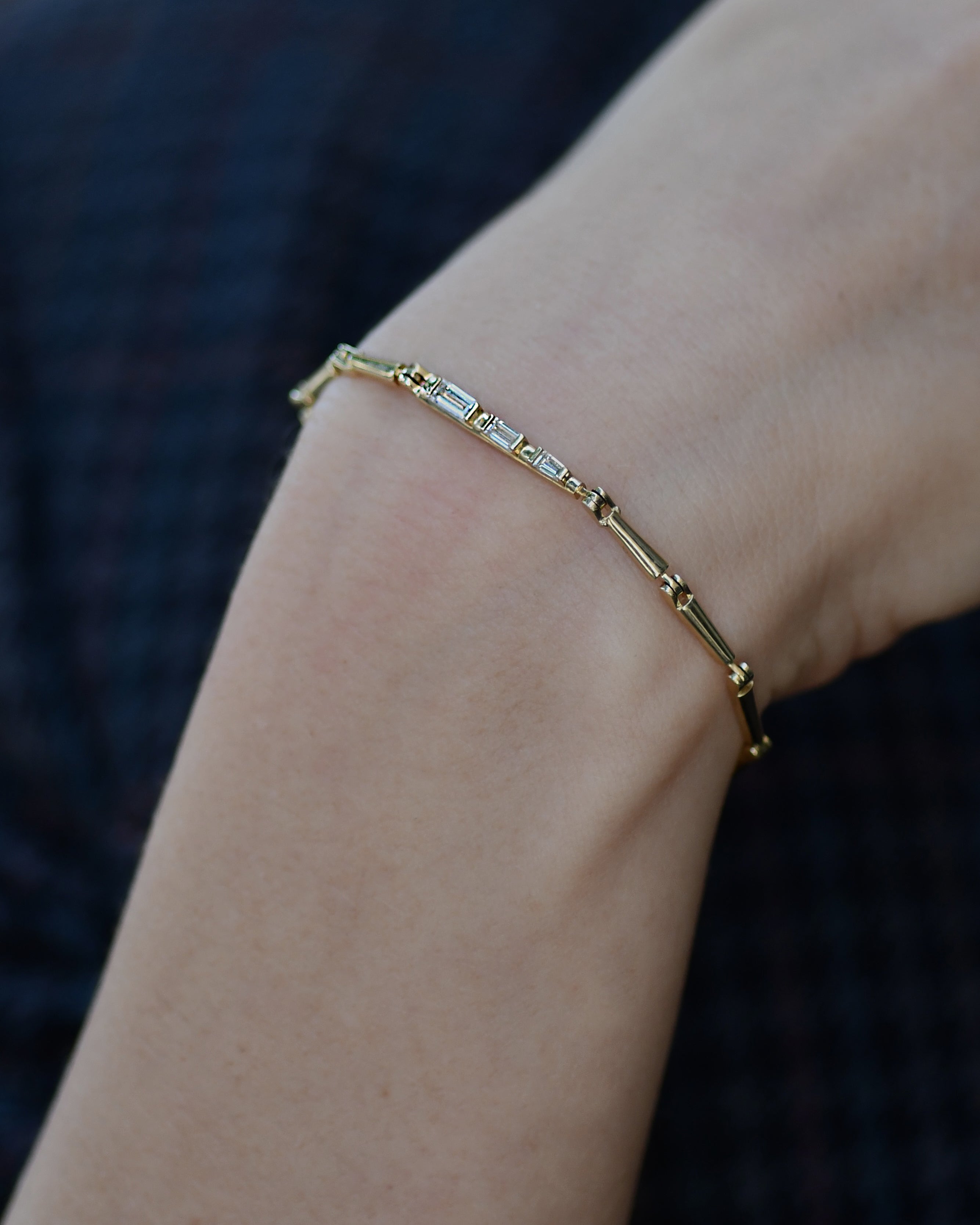 A gold bracelet with white diamond saccents, displayed on a wrist