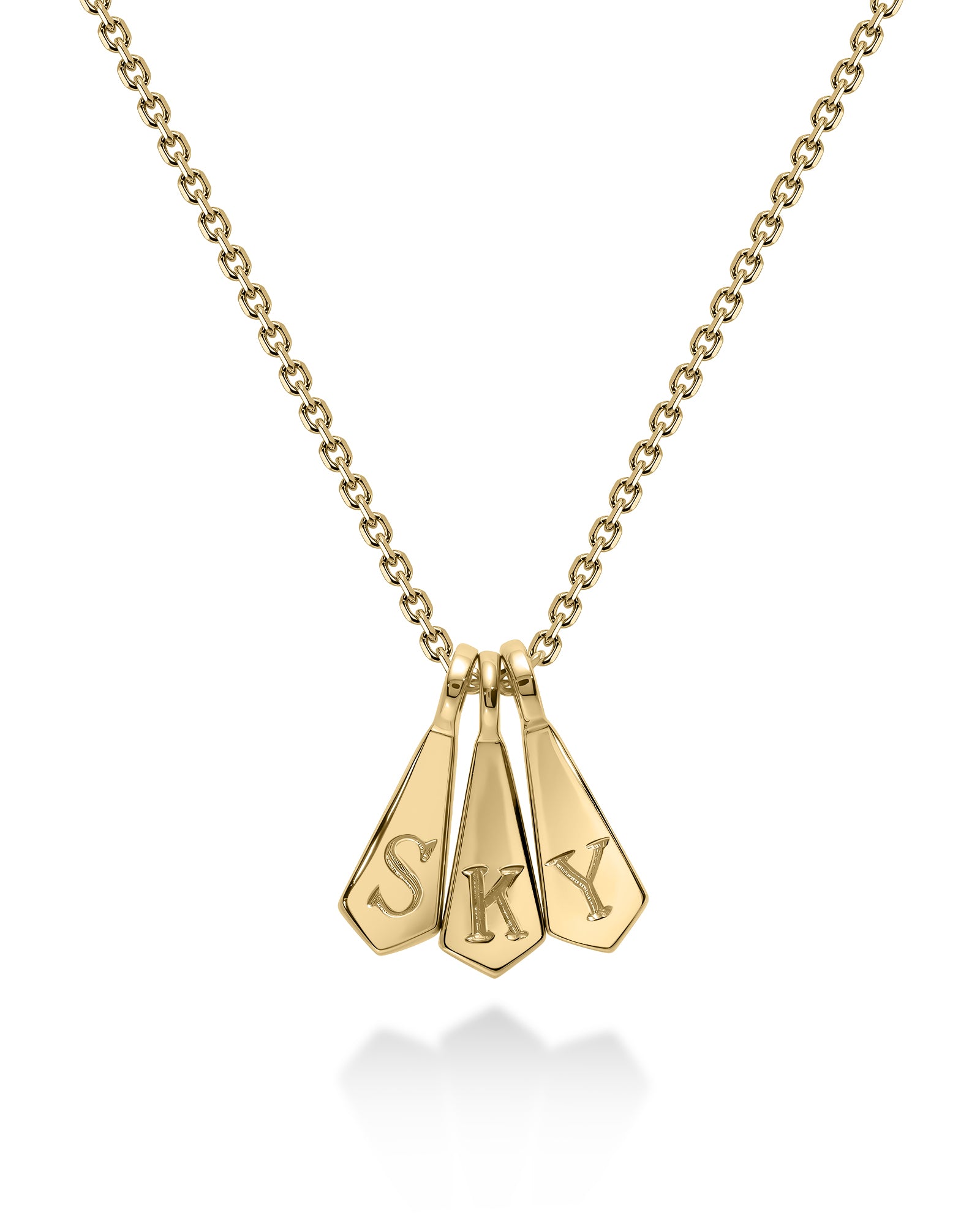 A gold chain necklace with three dangling arrowhead-shaped charms engraved with the letters 'S', 'K', and 'Y', shown on a white background with a soft reflection below.