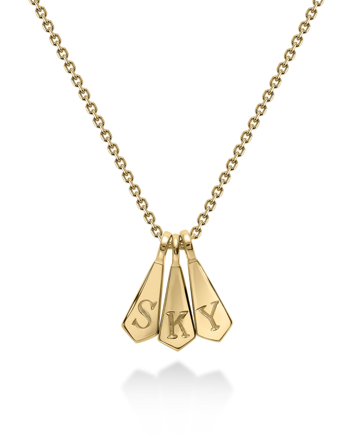 A gold chain necklace with three dangling arrowhead-shaped charms engraved with the letters 'S', 'K', and 'Y', shown on a white background with a soft reflection below.