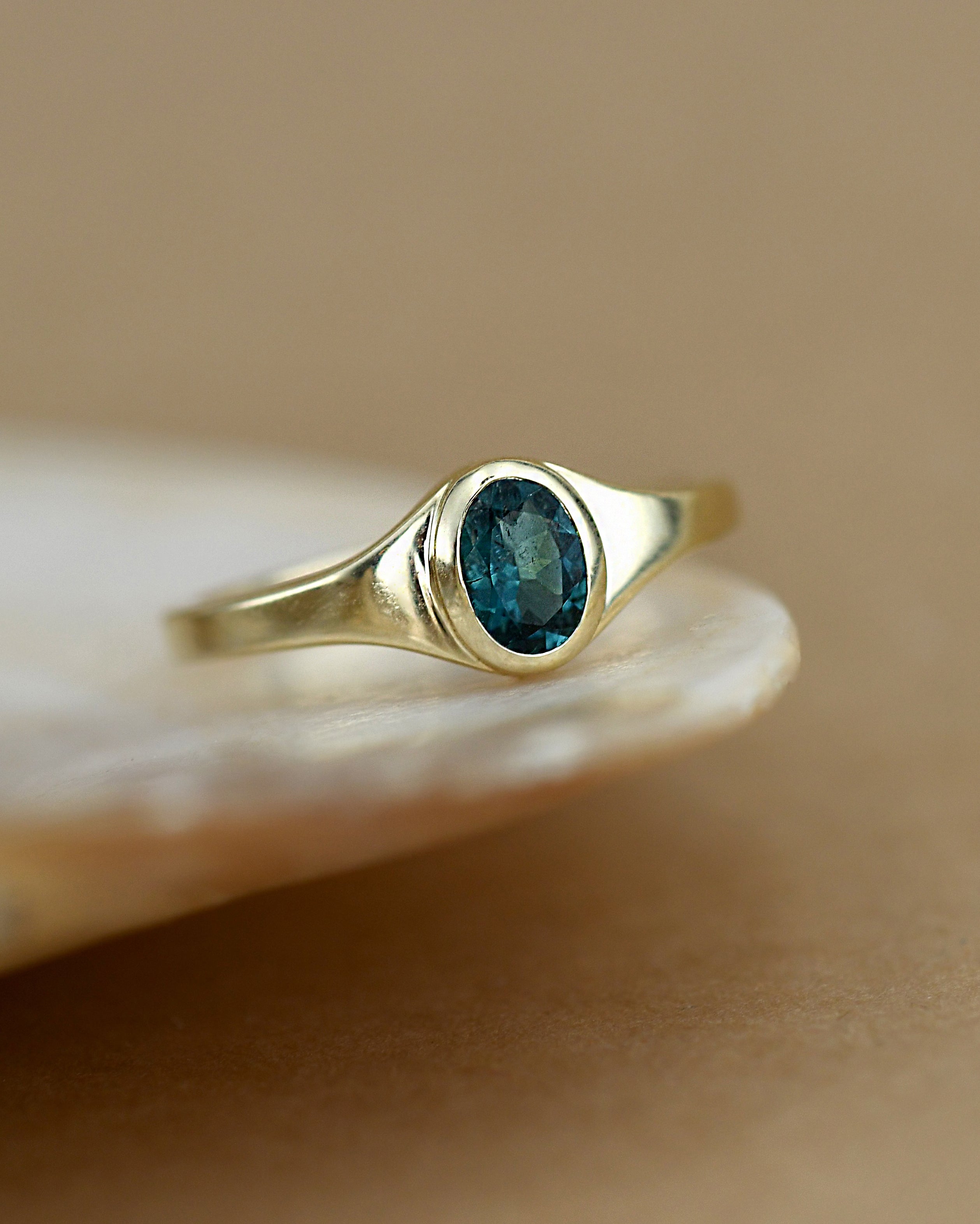 Gold ring with a blue gemstone on a beige background