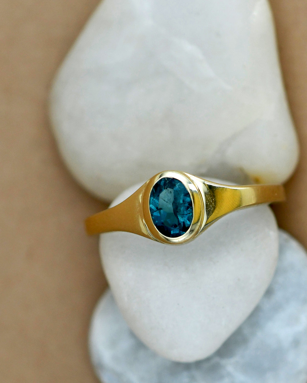 Gold ring with a blue gemstone on a white stone surface