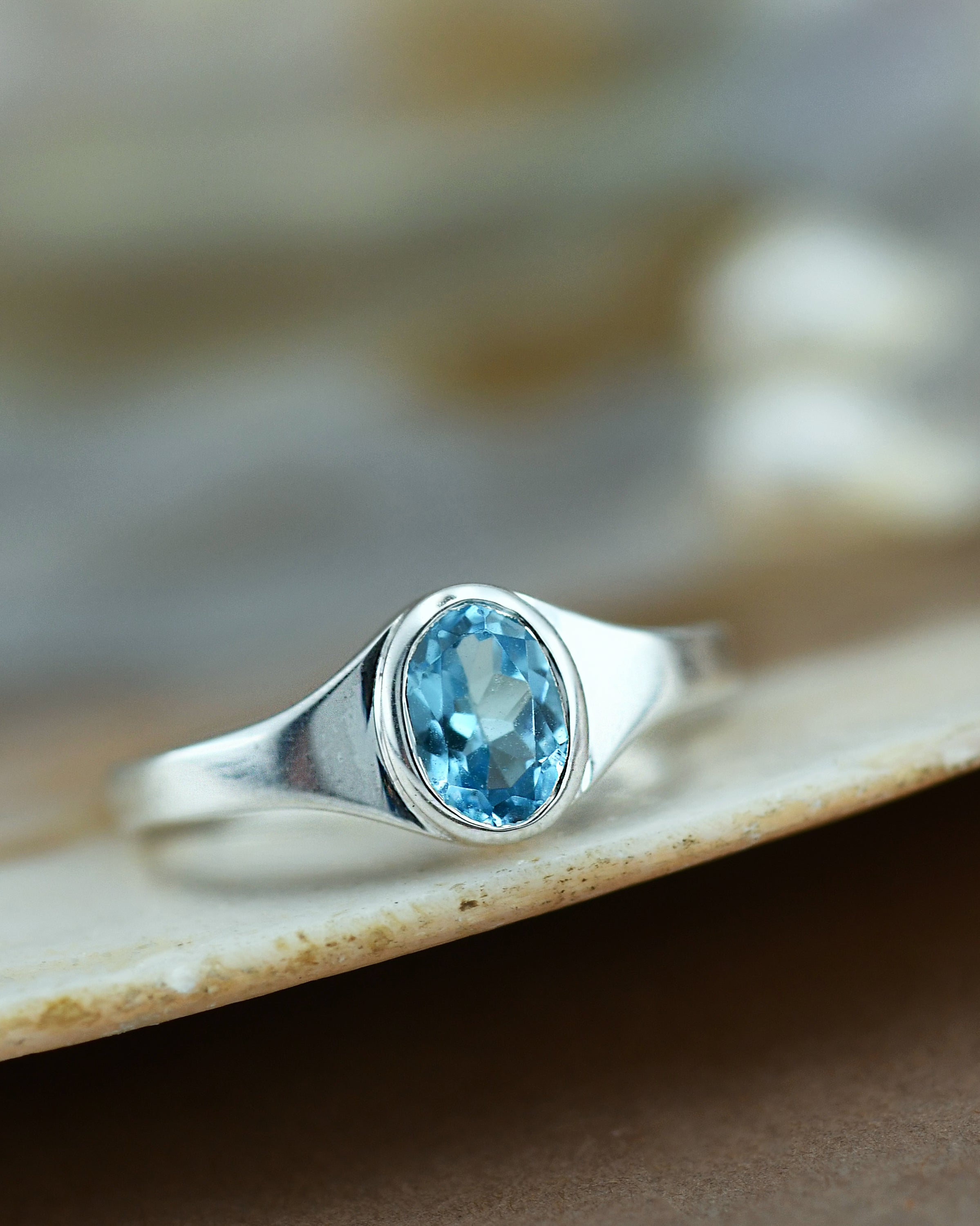Silver ring with a blue gemstone on a textured surface