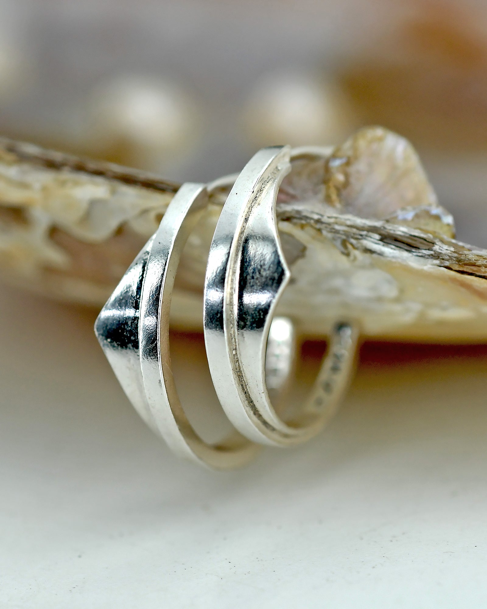Two silver earrings on a textured surface