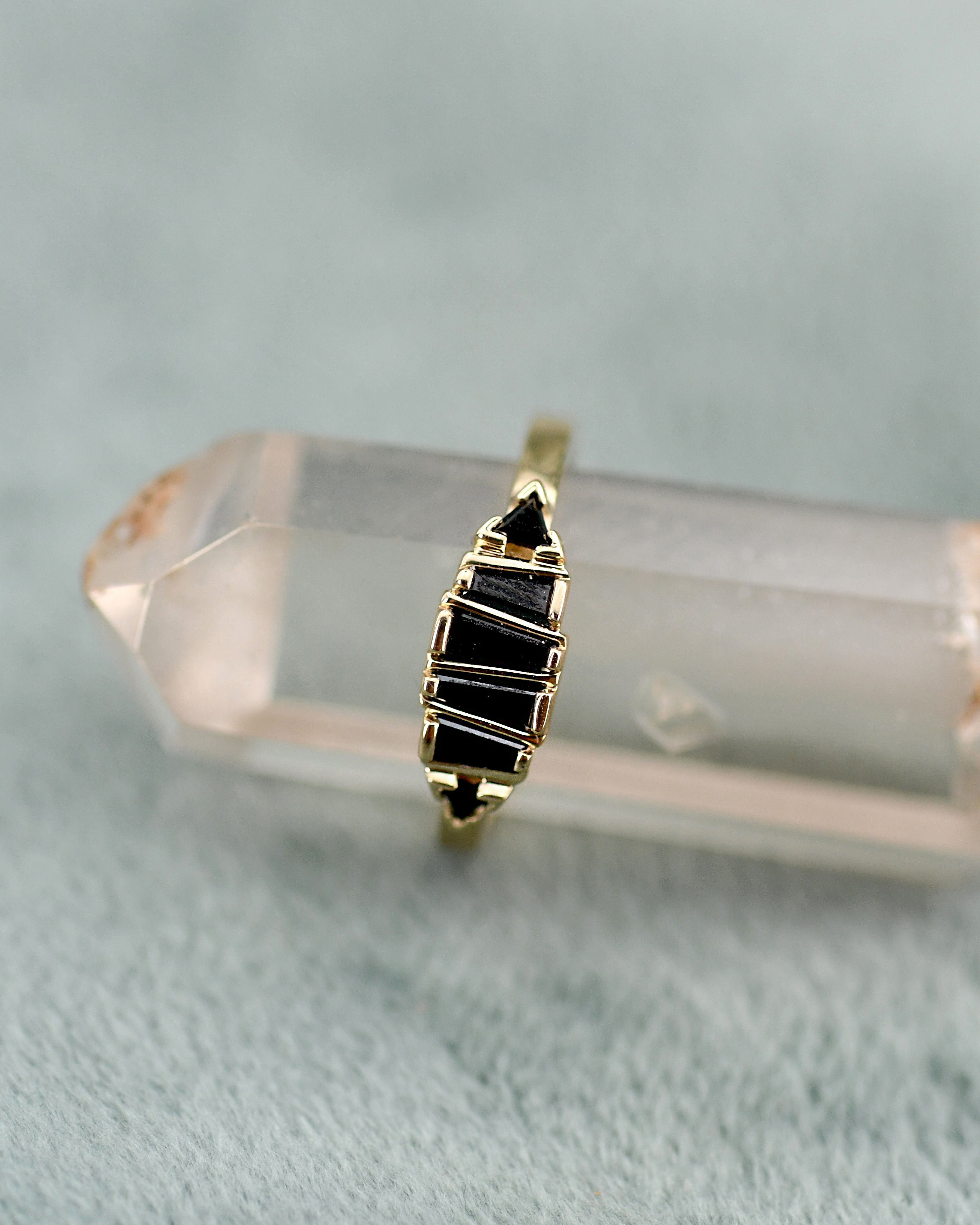 A gold ring with black triangular diamonds