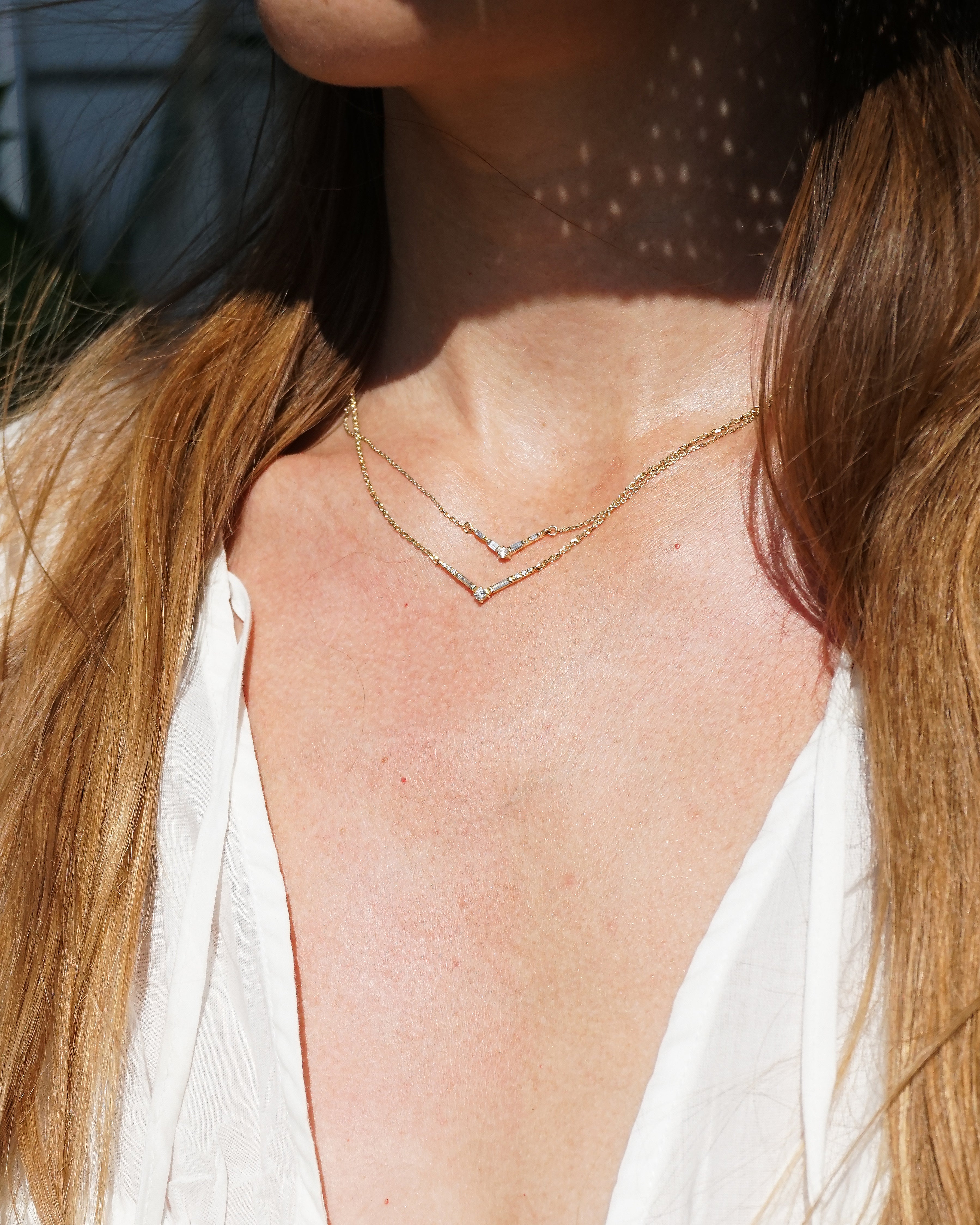 Close-up of a person wearing a delicate gold necklace with a blurred background