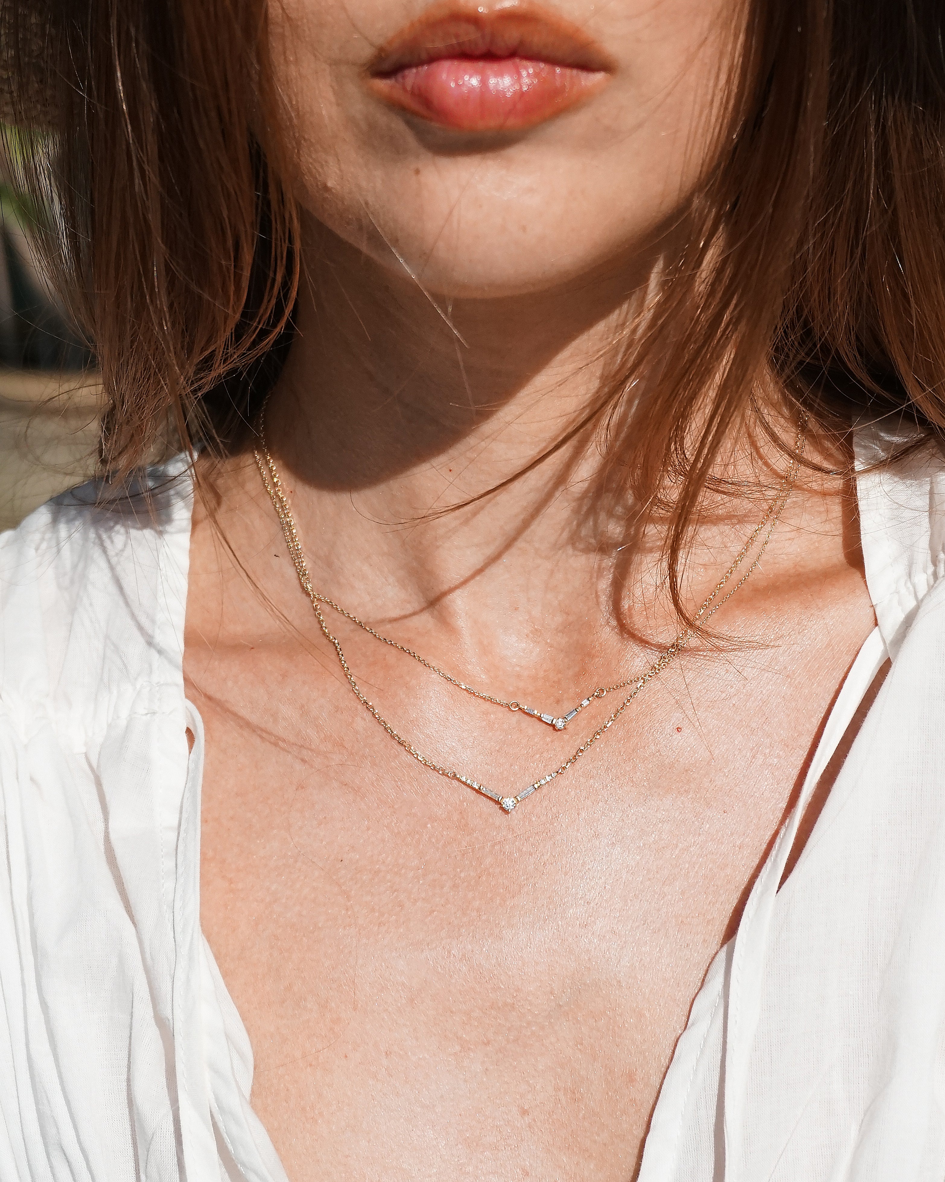 Close-up of a person wearing a delicate necklace with a blurred background