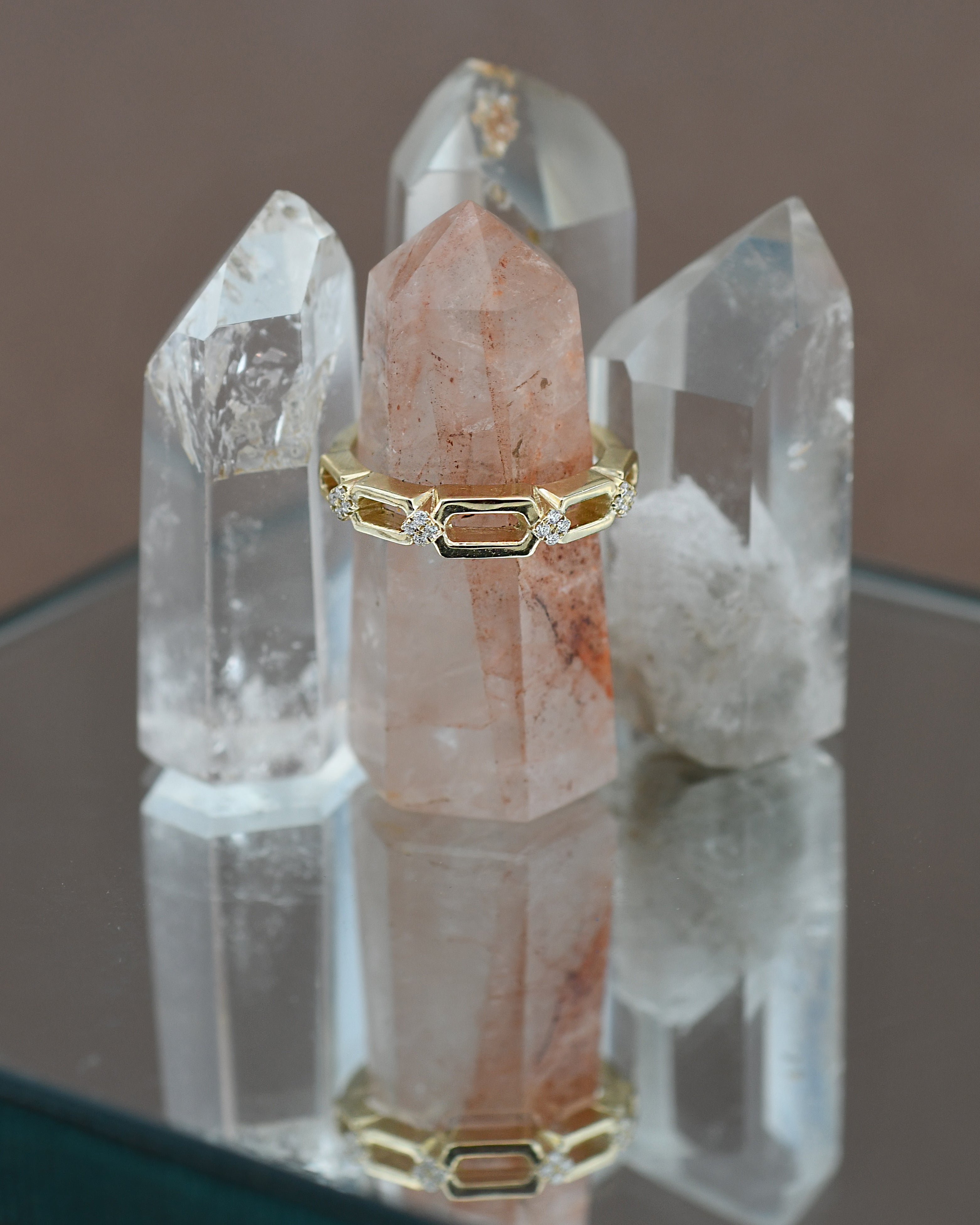 Gold ring with diamonds on a pink stone with crystal formations in the background