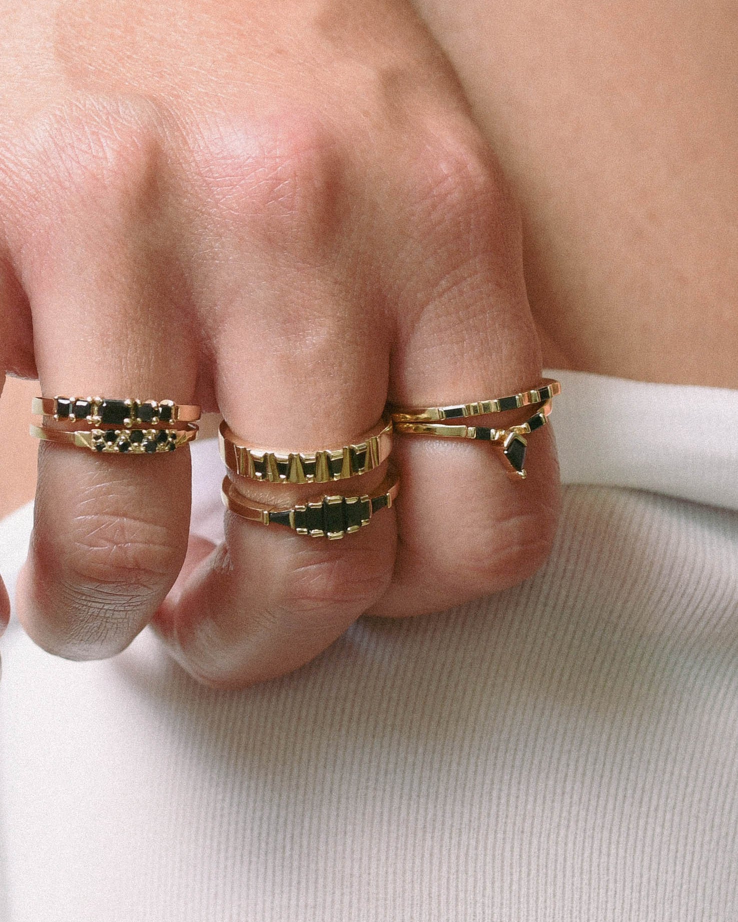 Close-up of a hand wearing gold rings with black diamonds