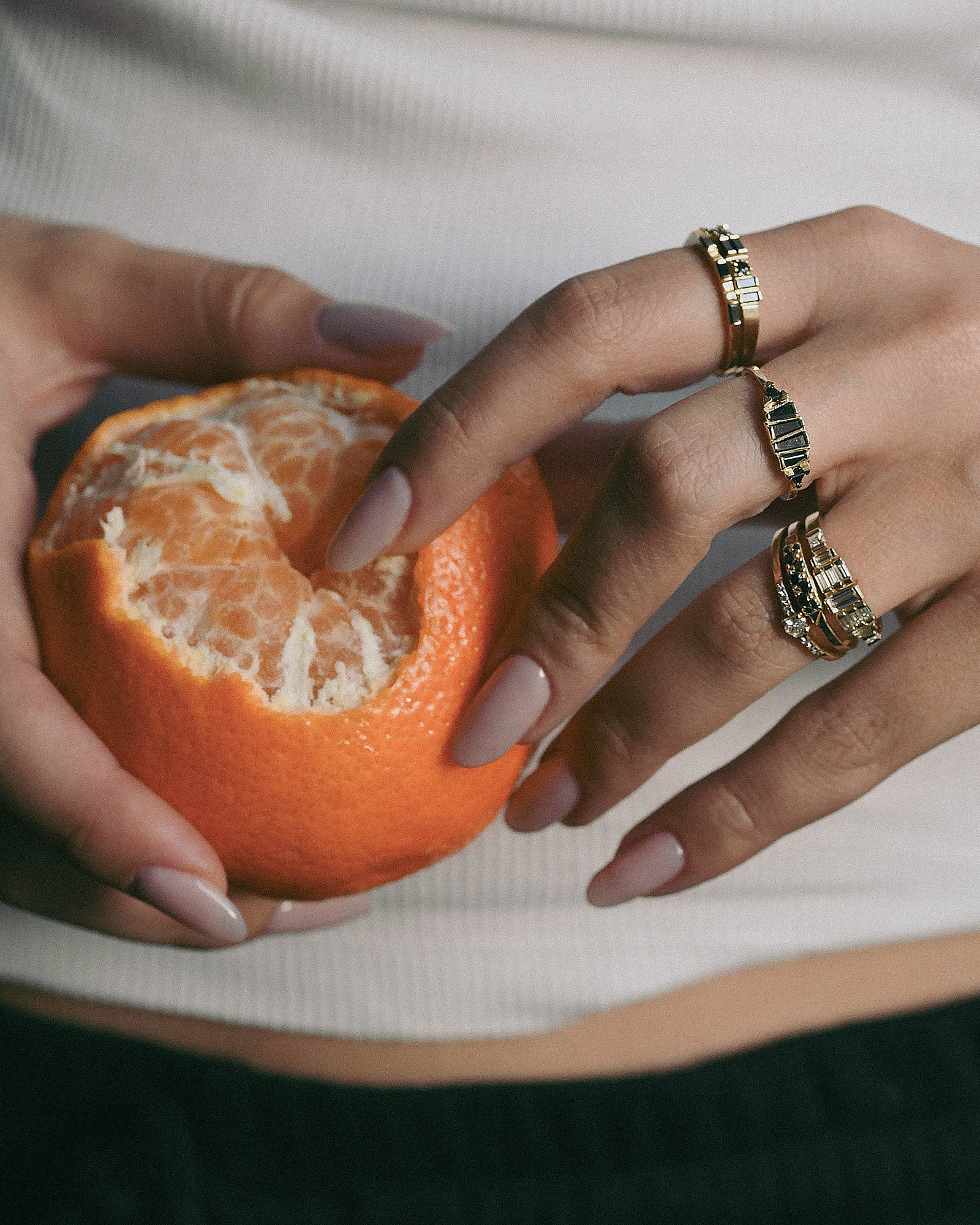 A close-up of a person's hand with gold rings and black diamonds 