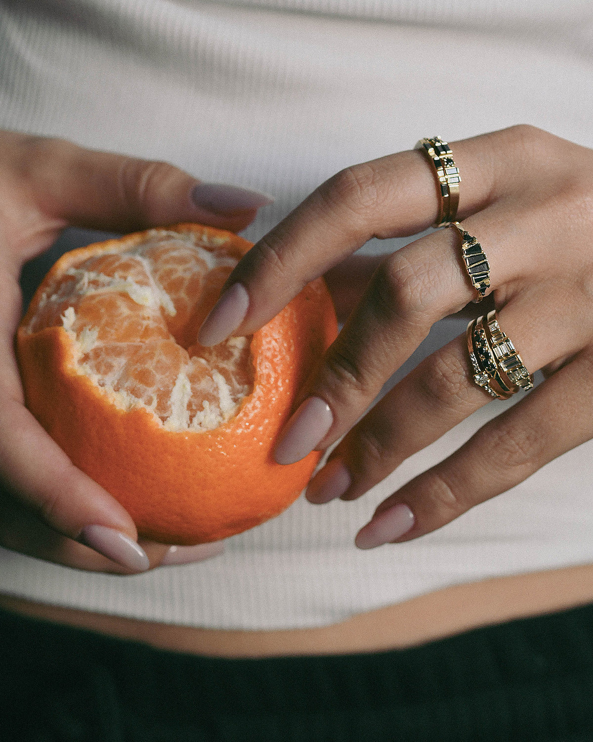 A close-up of a person's hand with gold rings and black diamonds 