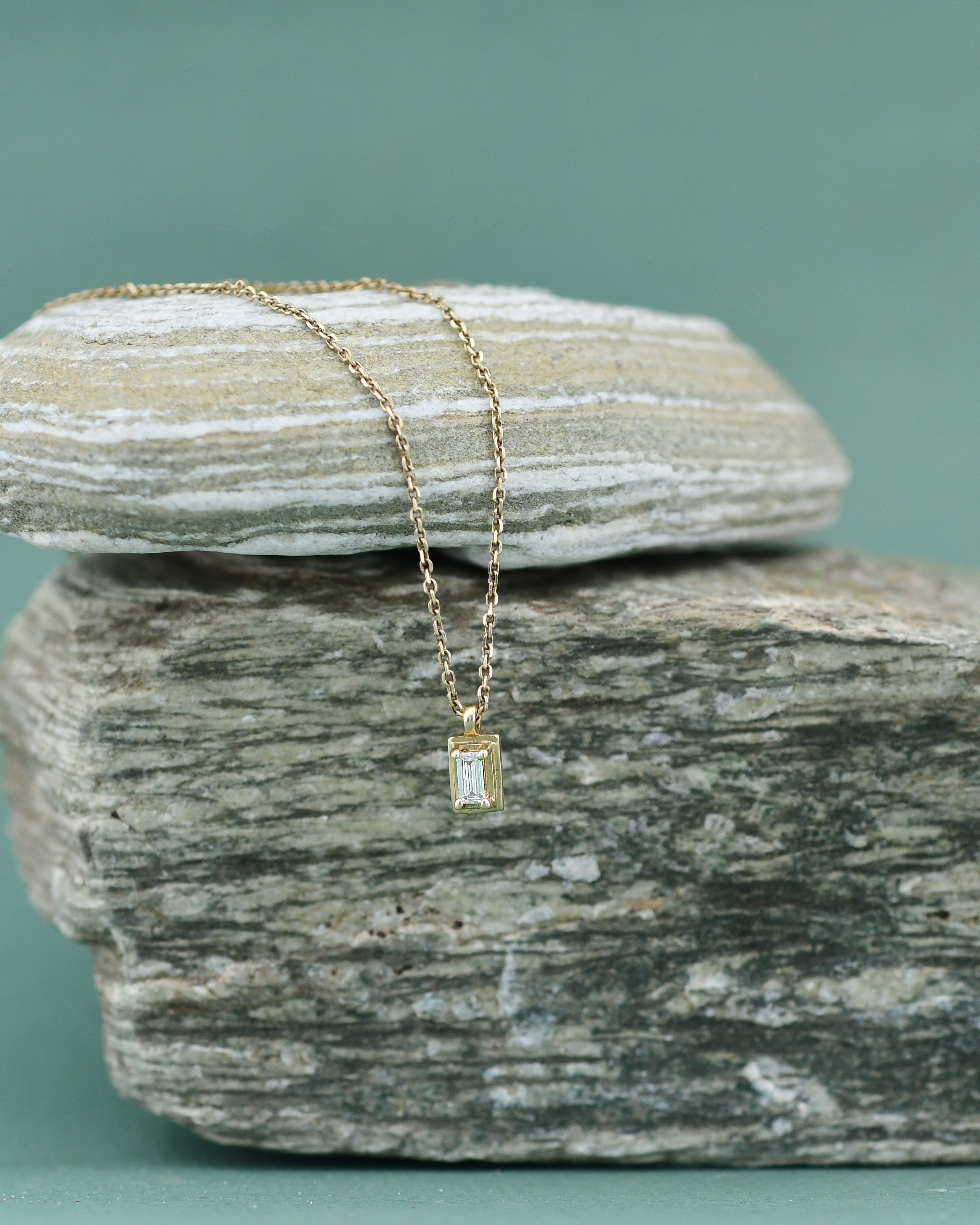 A white diamond necklace with a gold chain and a rectangular-shaped diamond pendant.