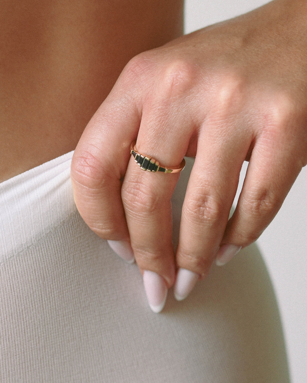 Close-up of a hand wearing a gold ring with black diamonds