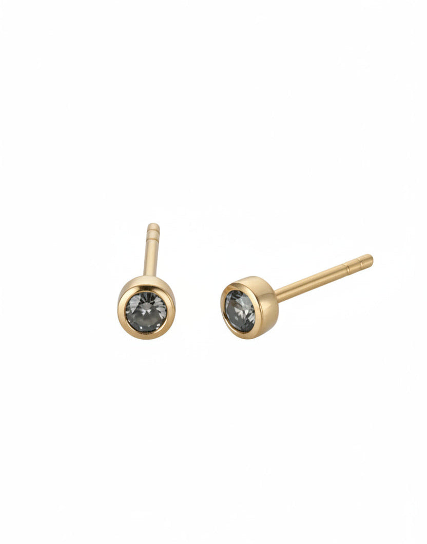 A pair of stud earrings with gold settings and single visible diamonds, displayed against a white background.