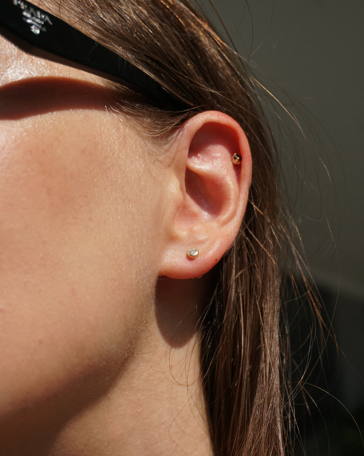 Close-up of an ear with earrings against a neutral background