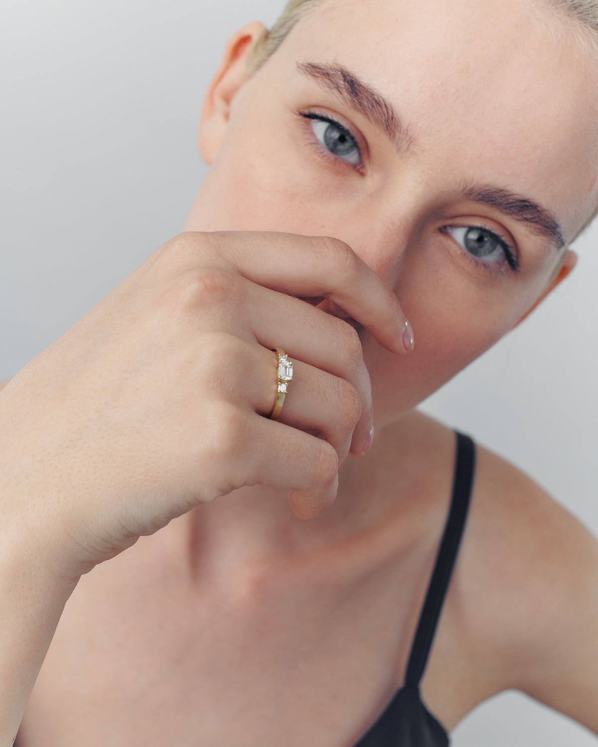 A close-up image of a woman's hand with a diamond ring on her finger